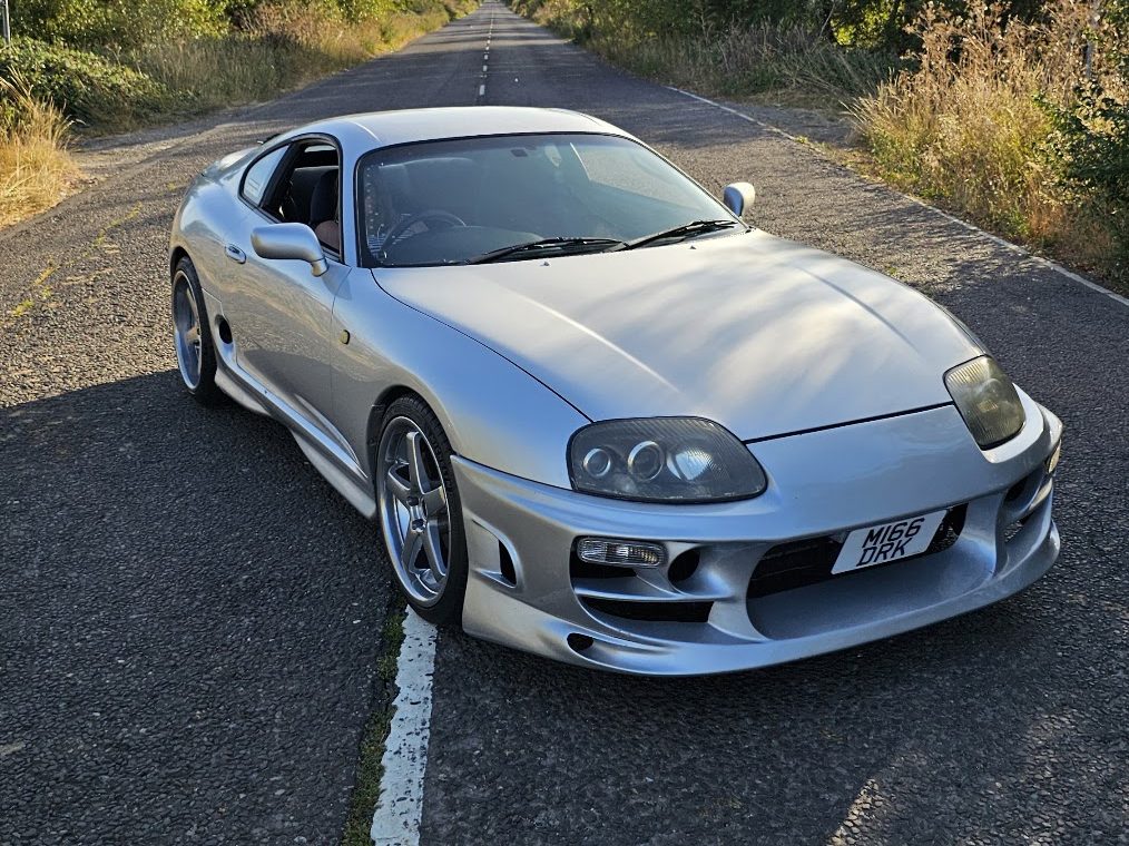 Silver Toyota Supra MK4 on a country lane, as it appears when a sticker is scanned